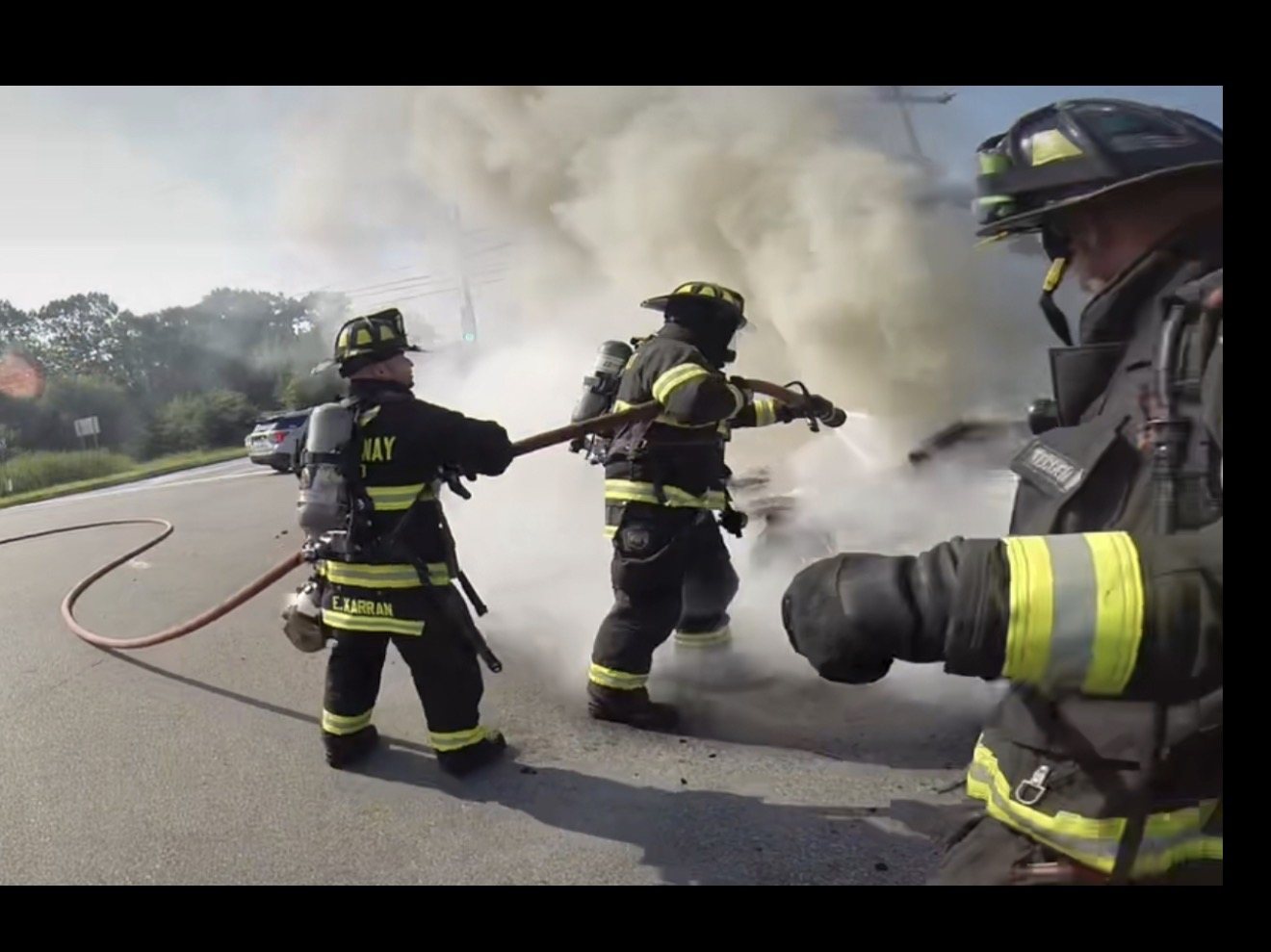 Firefighters advancing a hose line at a vehicle fire