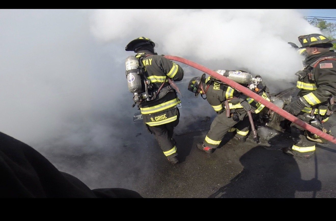 Firefighters working a vehicle fire in heavy smoke